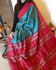 Red and green saree with patterns draped over a person, with a blurred background