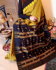 Person wearing a traditional saree with a patterned design, sitting on a chair.